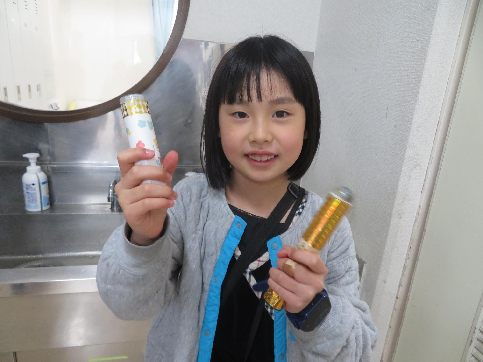 完成した万華鏡を持ってポーズしている小学生の写真