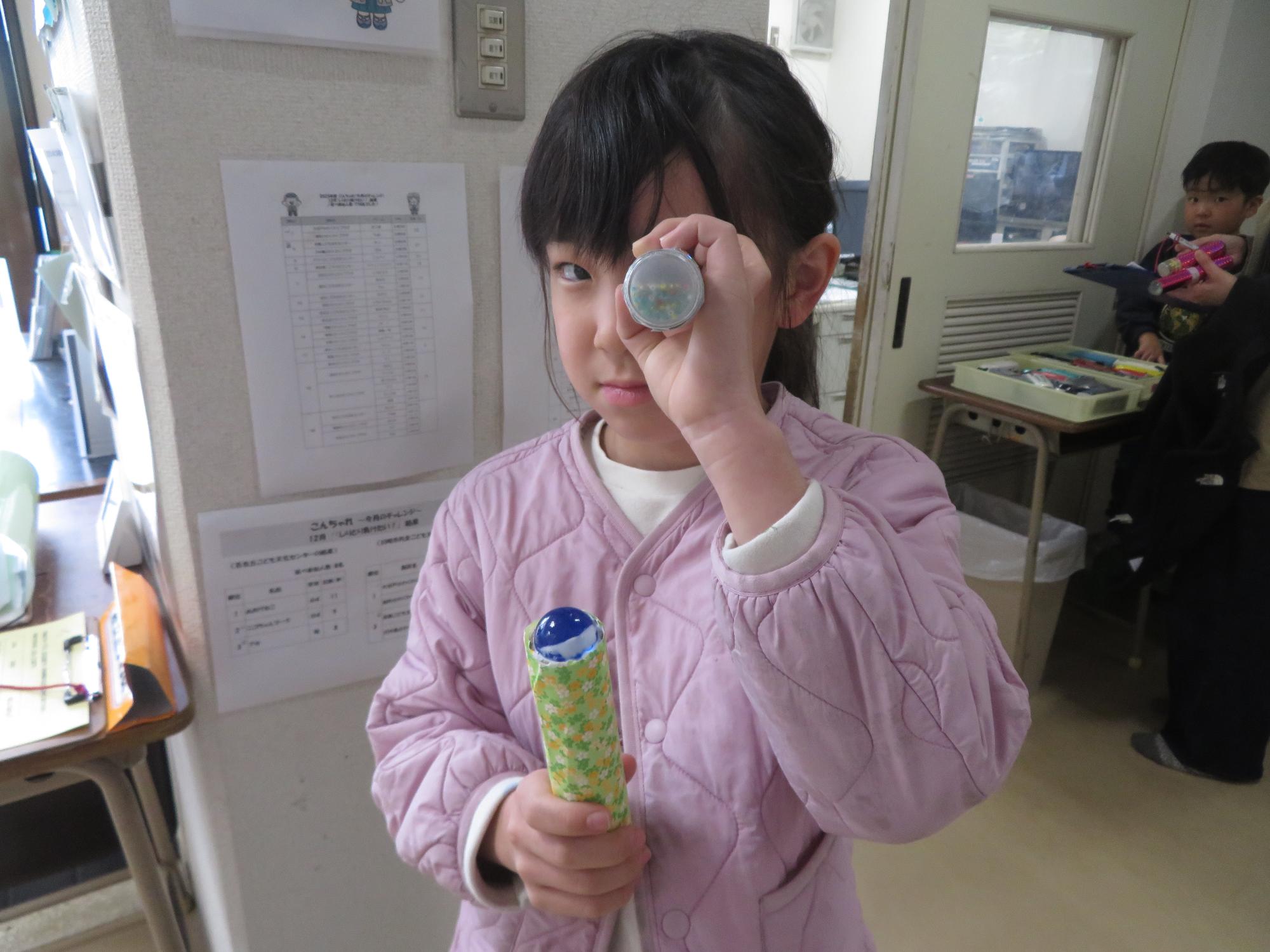 完成した万華鏡を持ってポーズしている小学生の写真