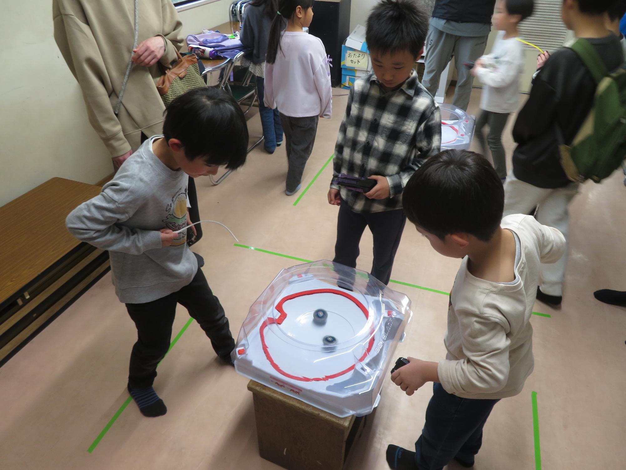 ベイブレード対戦をしている小学生2人の写真