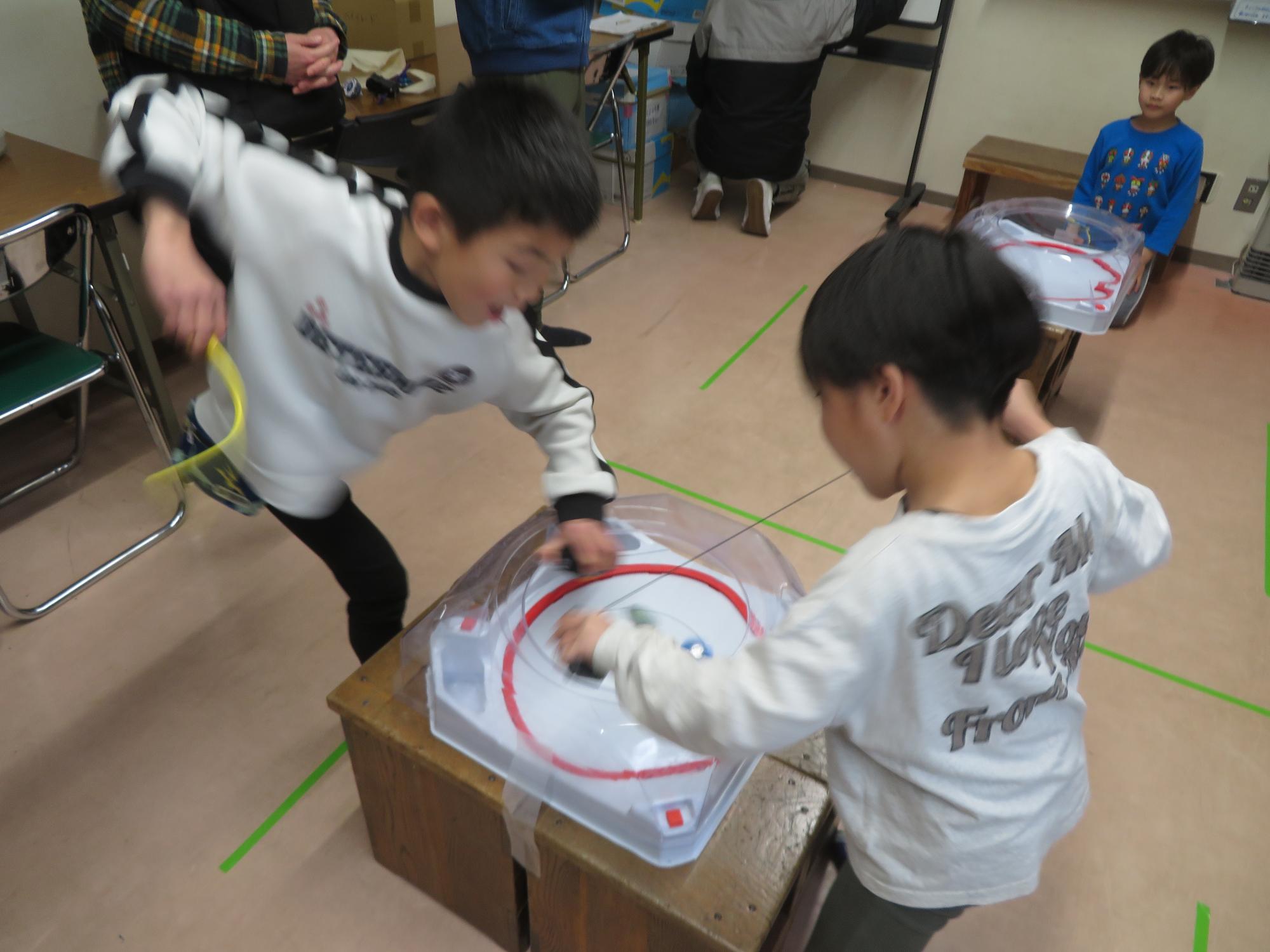 ベイブレード対戦をしている小学生2人の写真