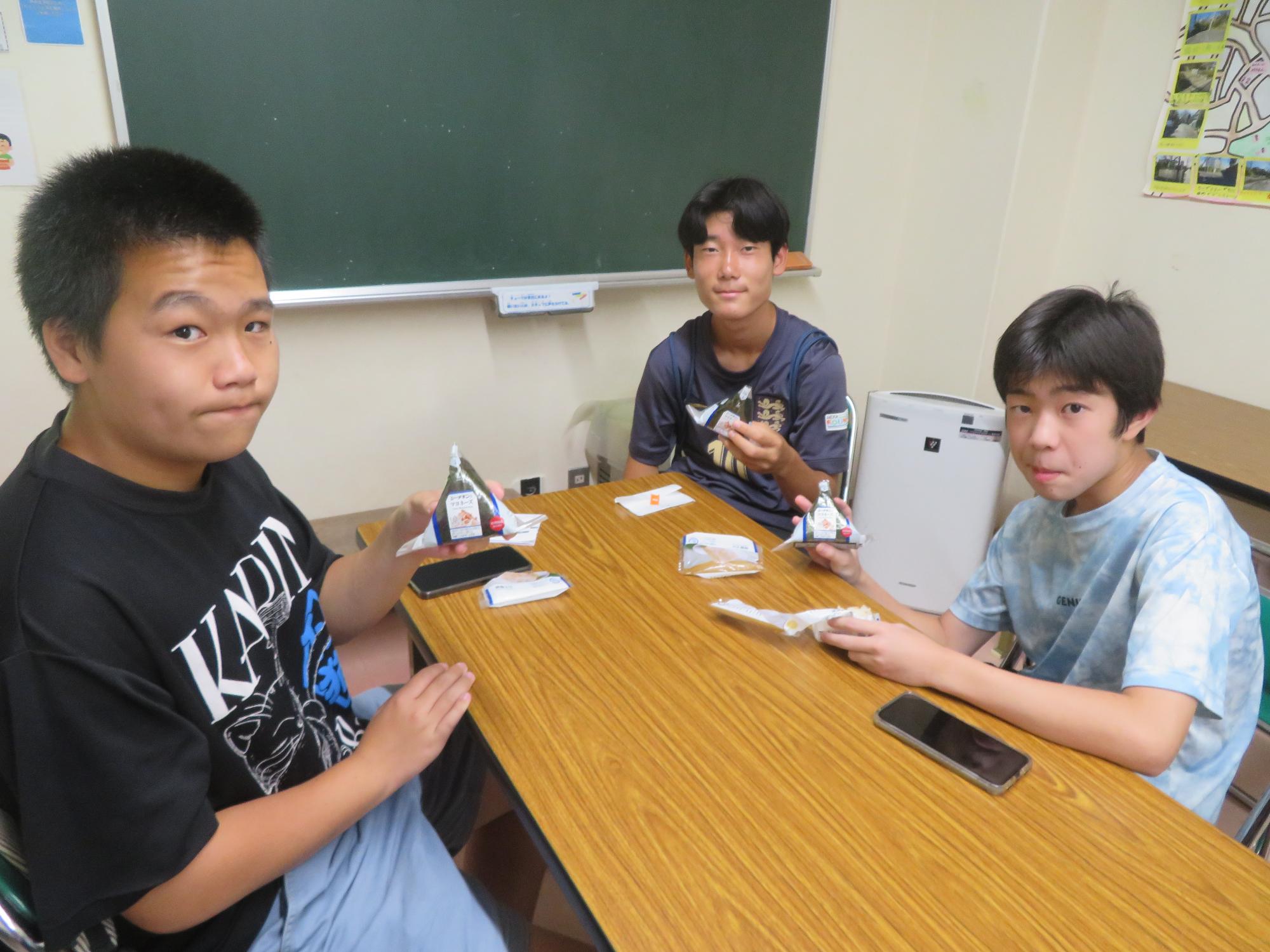 中学生男子3名がローソンのおにぎりをもらって食しているところの写真