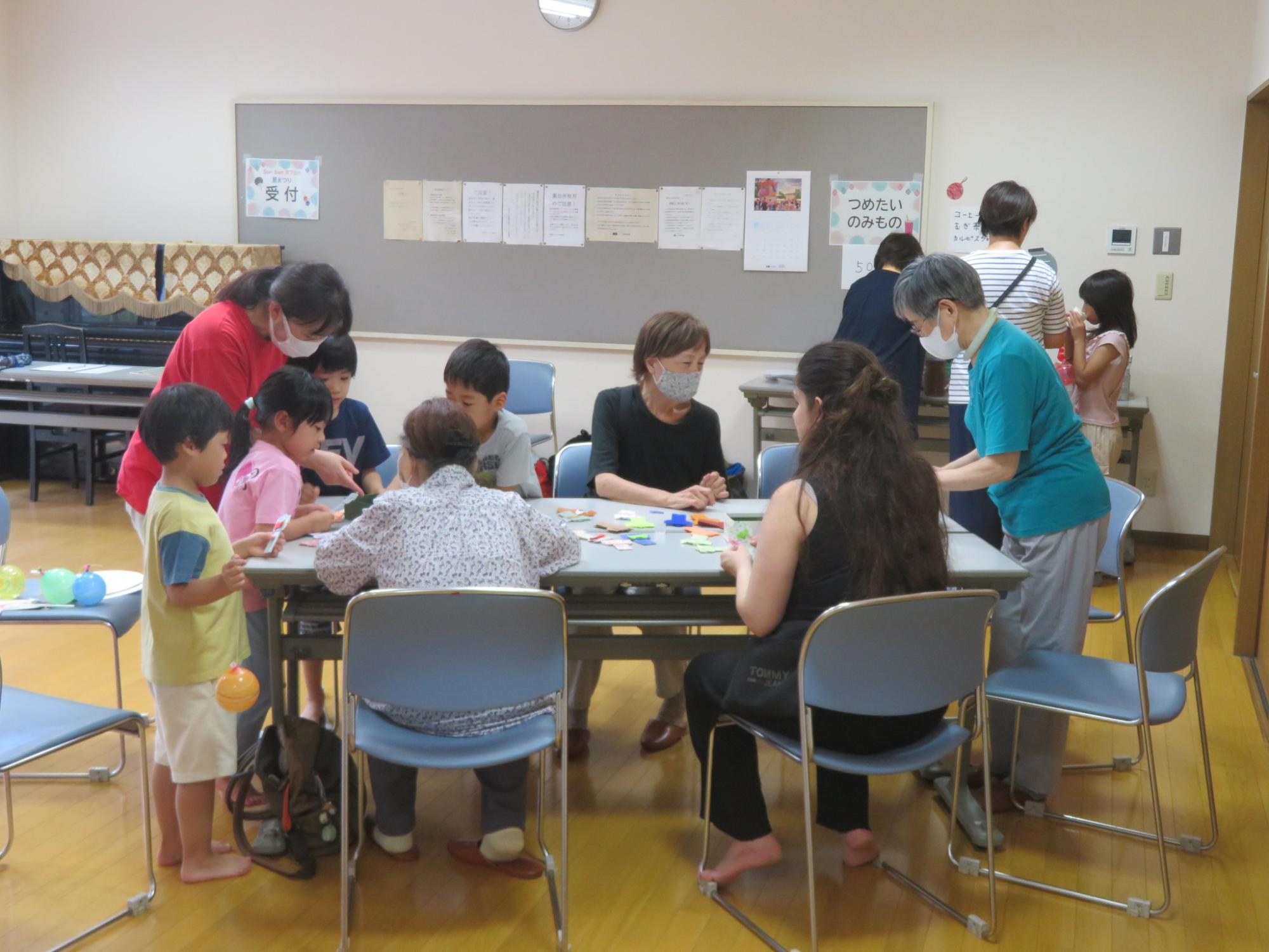 子どもと大人が折紙で着物作りをしている写真