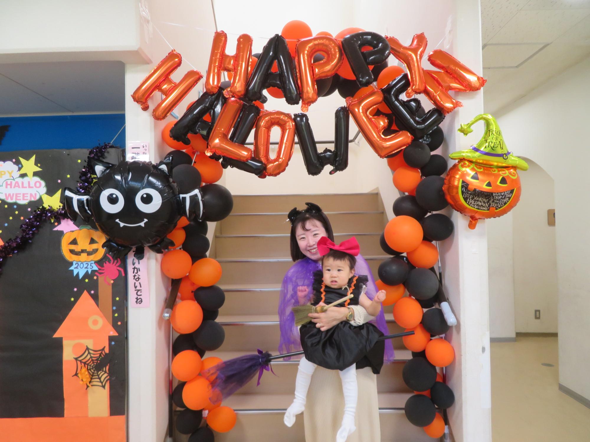 バルーンアーチの前でポーズをとる親子の写真