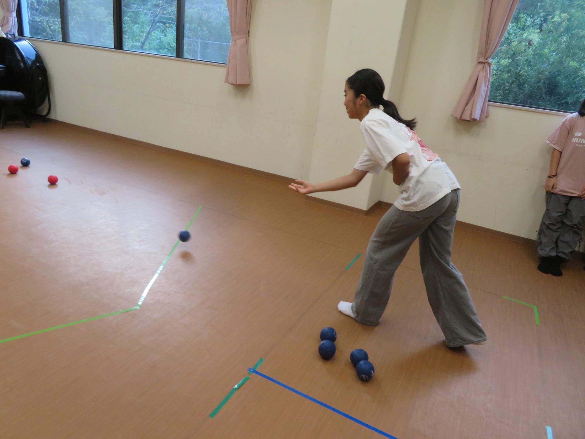 中学生女子がボッチャのボールを投げる写真