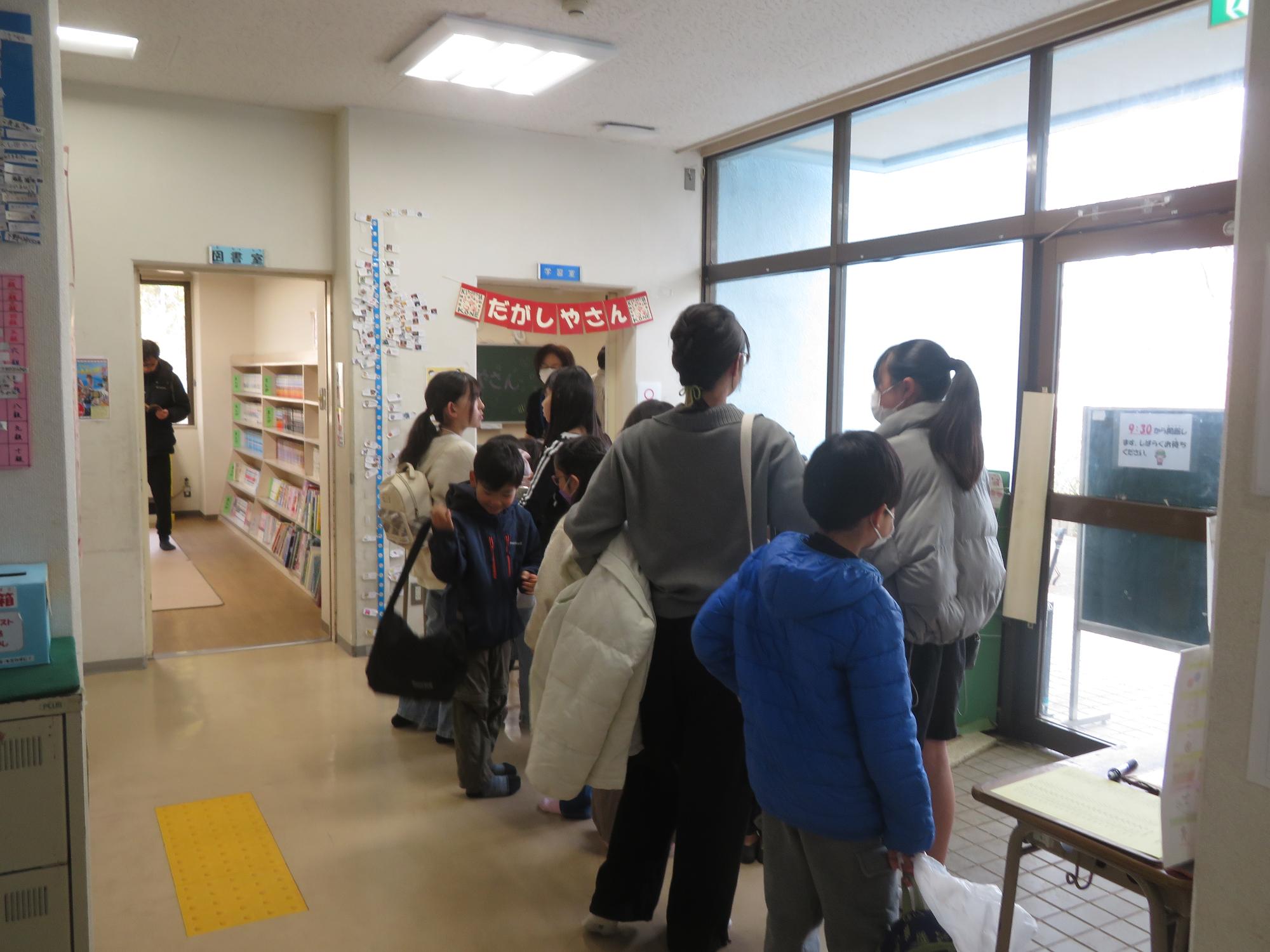 駄菓子屋さんの部屋の前に並ぶ子どもたちの写真