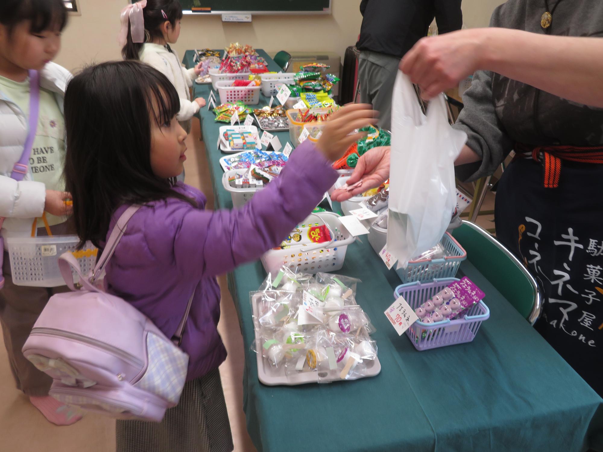 駄菓子屋さんから駄菓子を買う子どもの写真