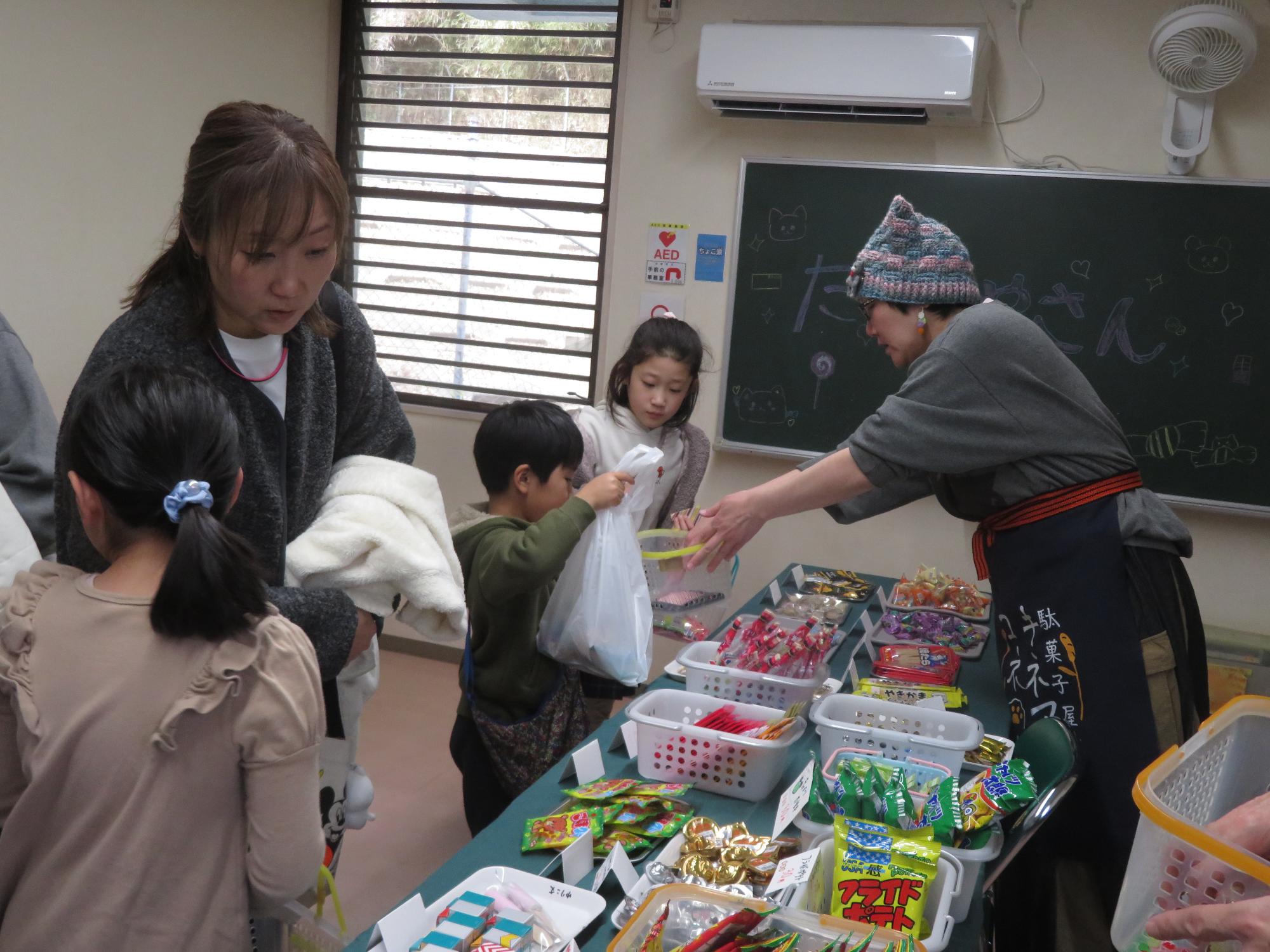 駄菓子屋さんから駄菓子を買う男の子の写真