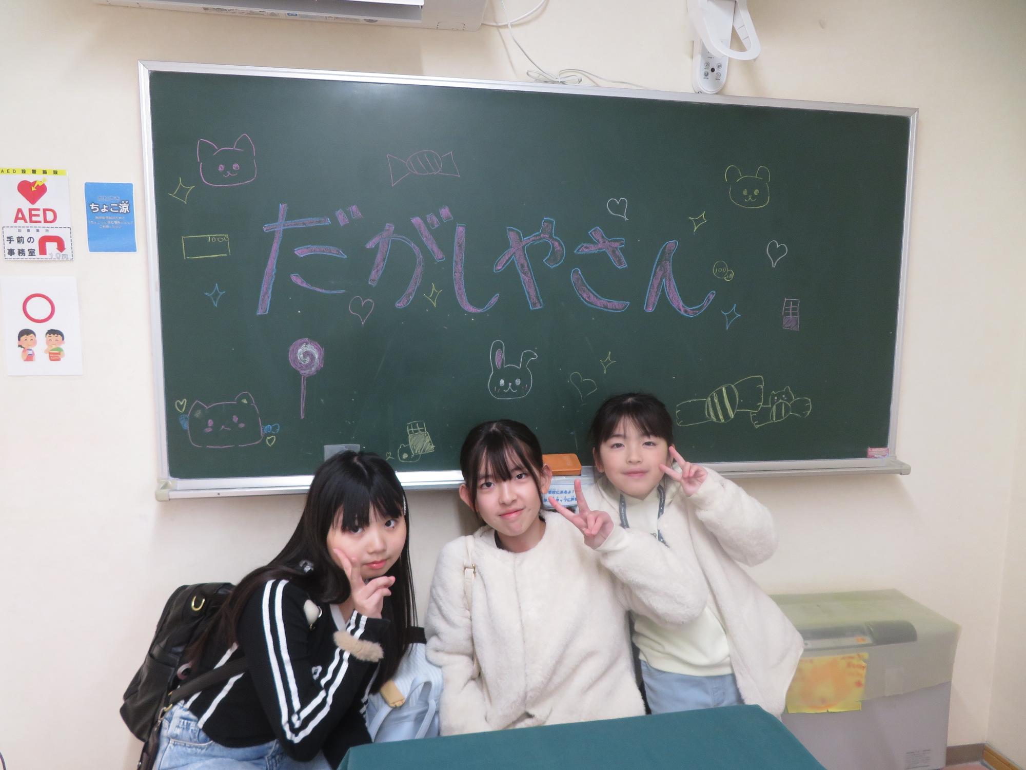 黒板の前でポースをとるこども達の写真