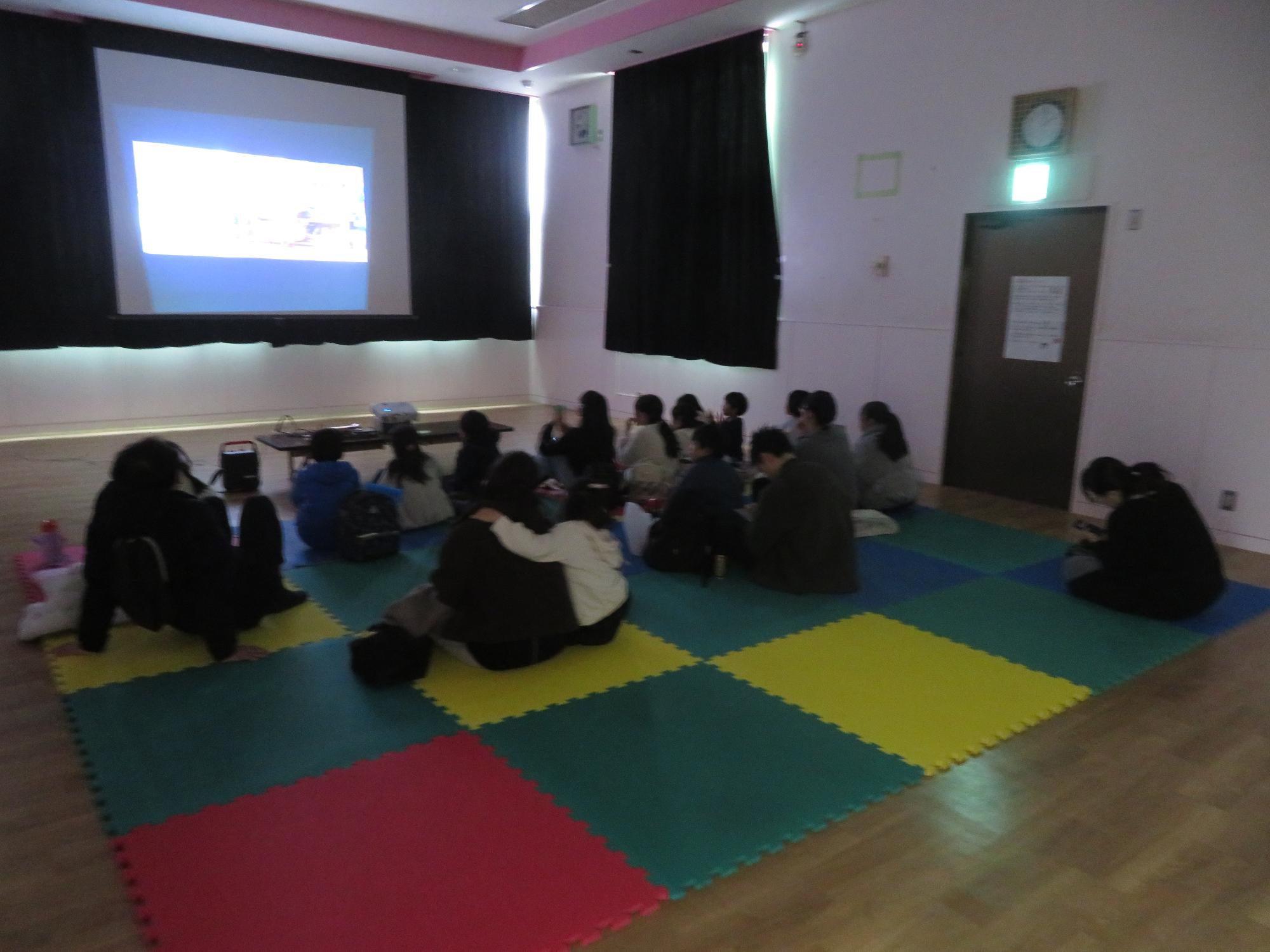 集会室で映画を観る参加者の写真