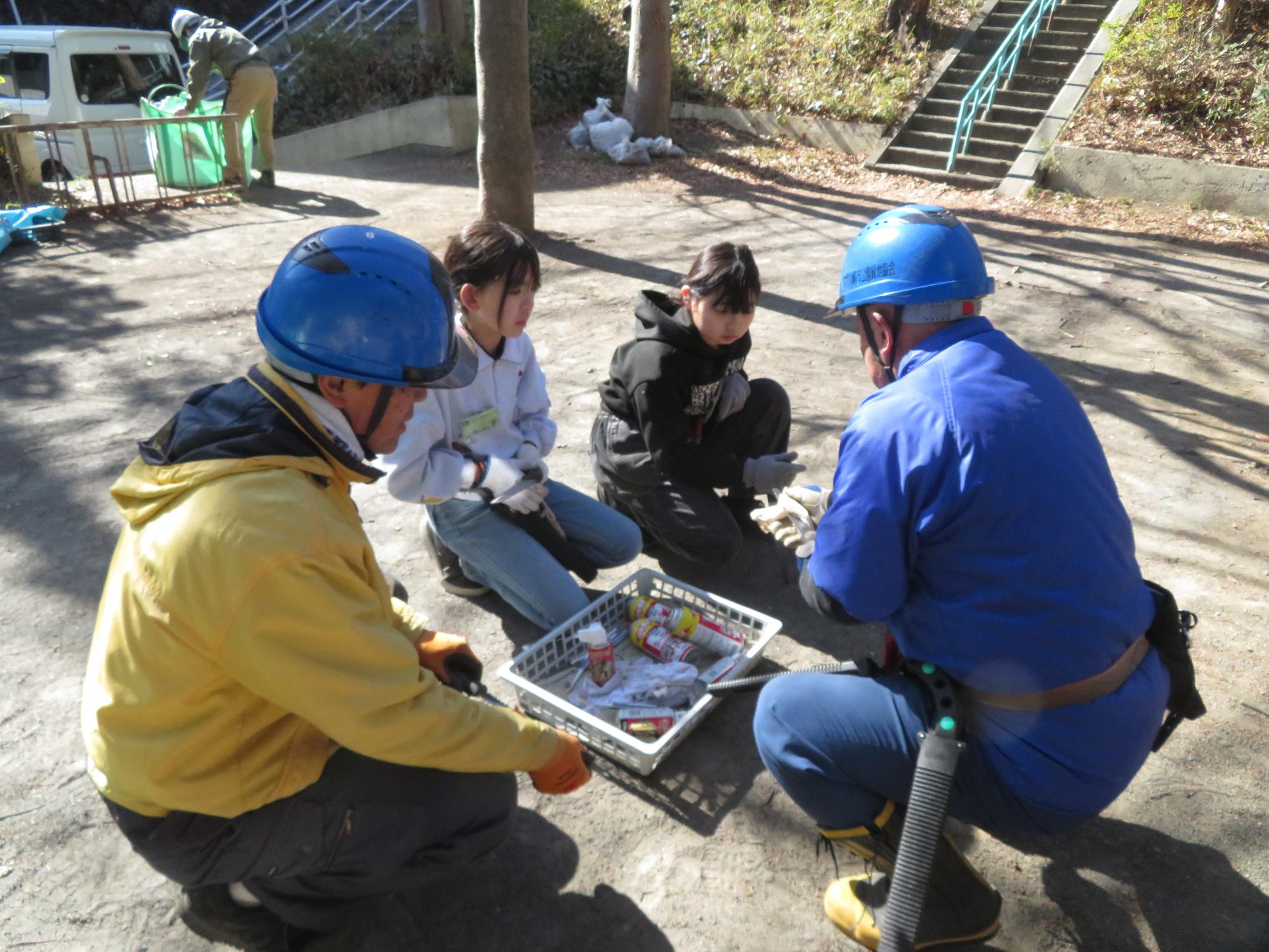 使った刃物の手入れの仕方を教わる子どもと大人の写真