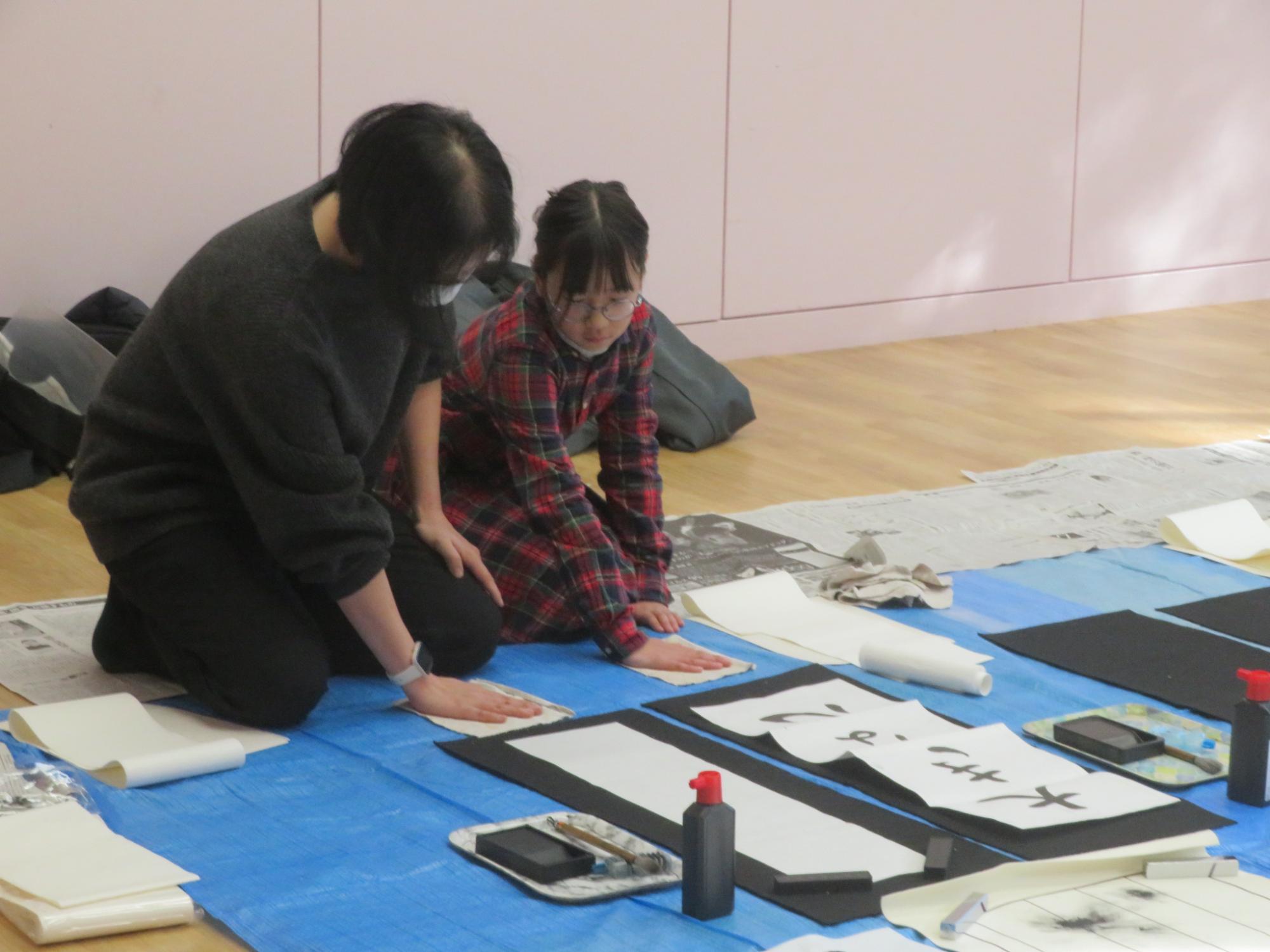 ぞうきんに手をあてて筆の動きを確認する講師と児童の写真