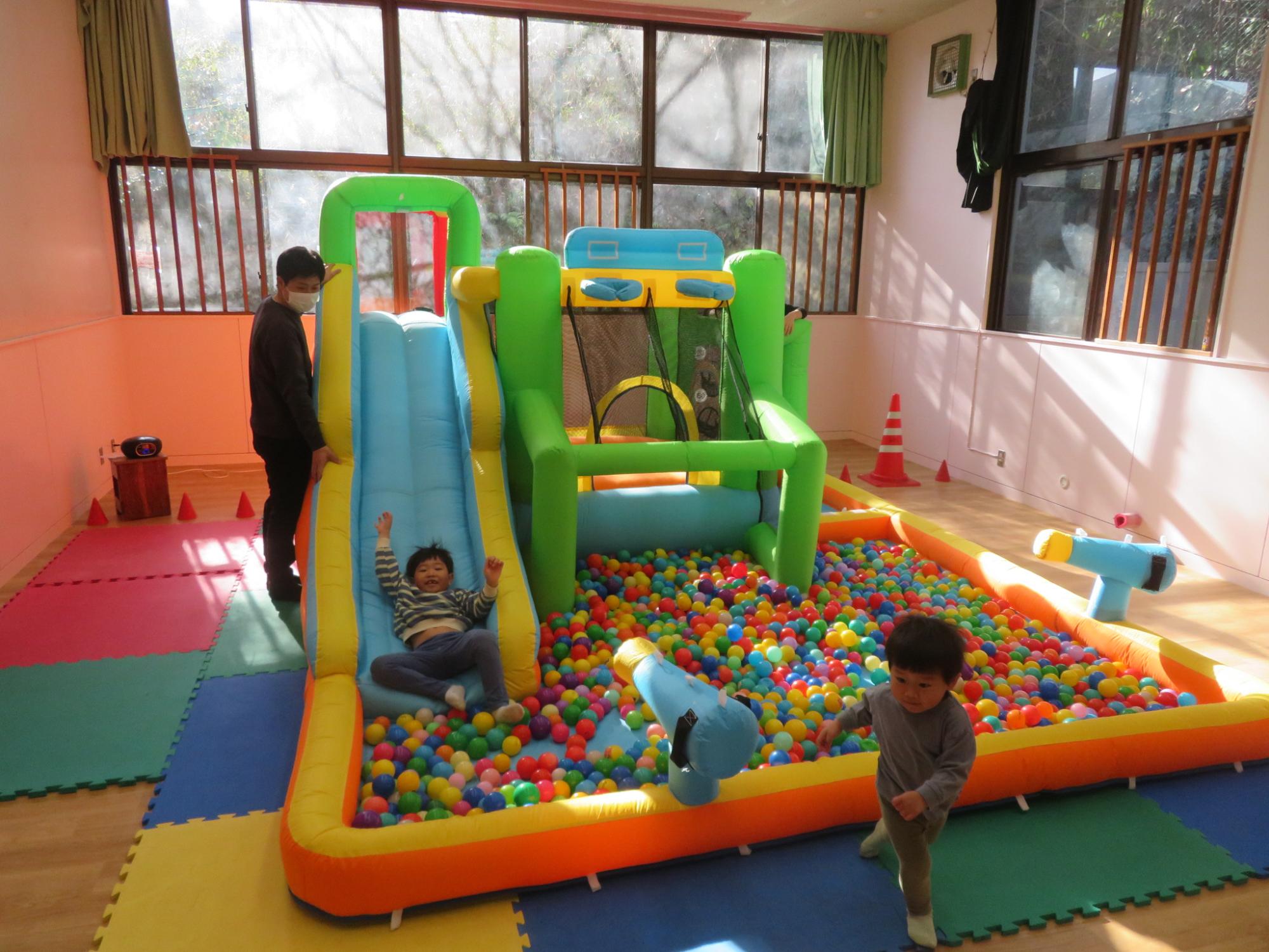 大型遊具で遊ぶ児童とそれを見守る保護者の写真