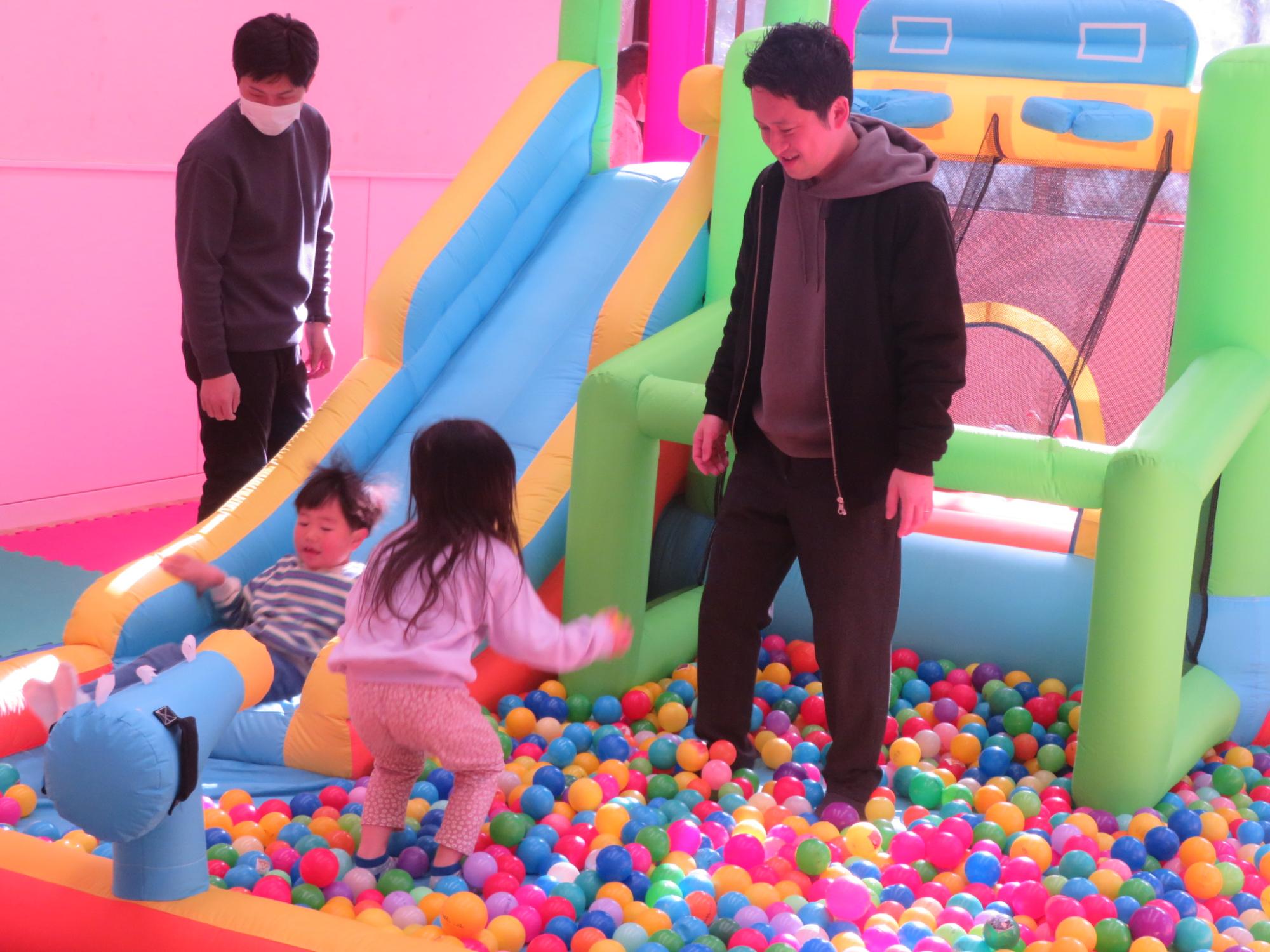 ボールプールの中で遊ぶ親子の写真