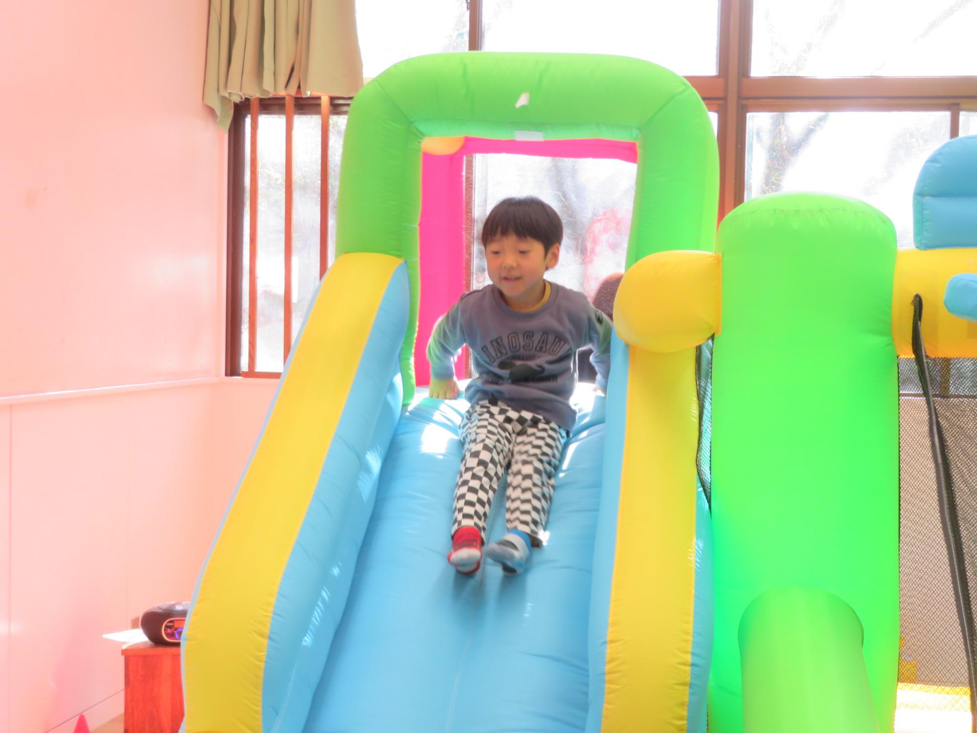 楽しそうに滑り台を滑る幼児の写真