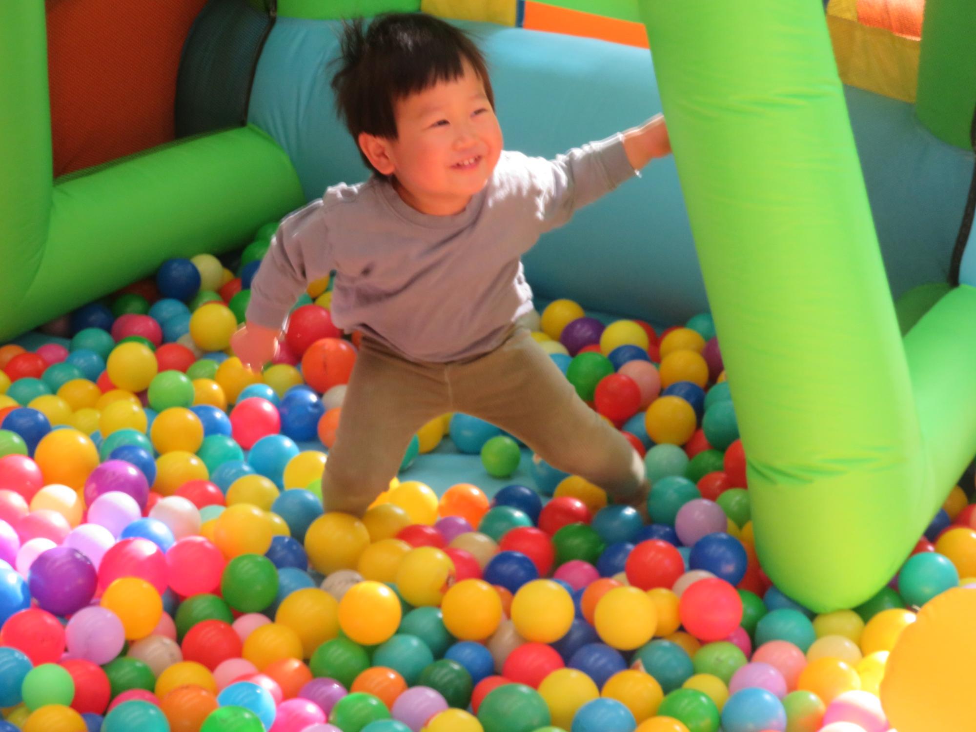 ボールプールの中で嬉しそうに遊ぶ幼児の写真