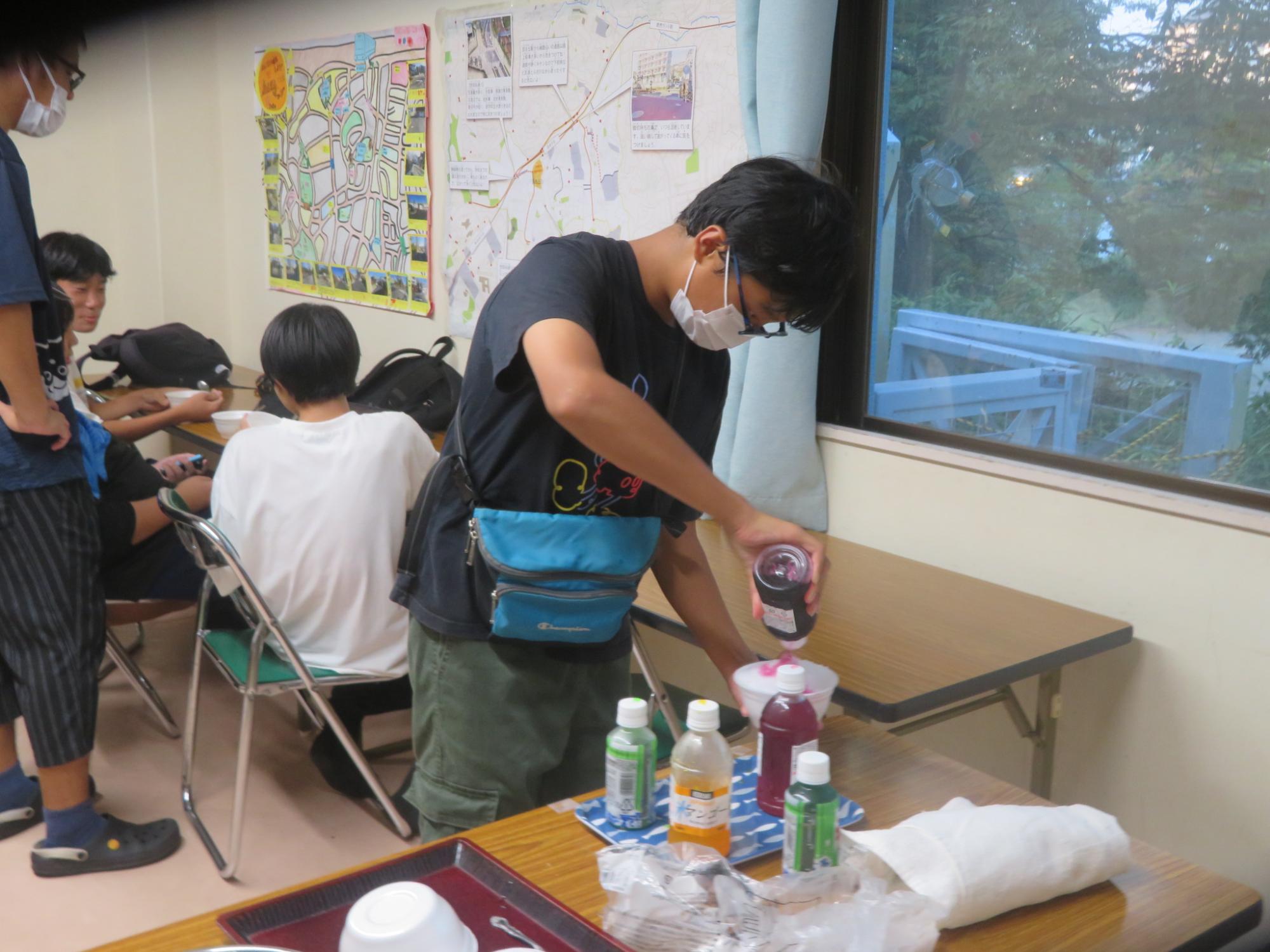 中学生男子が削った氷にかき氷のシロップをかけている写真