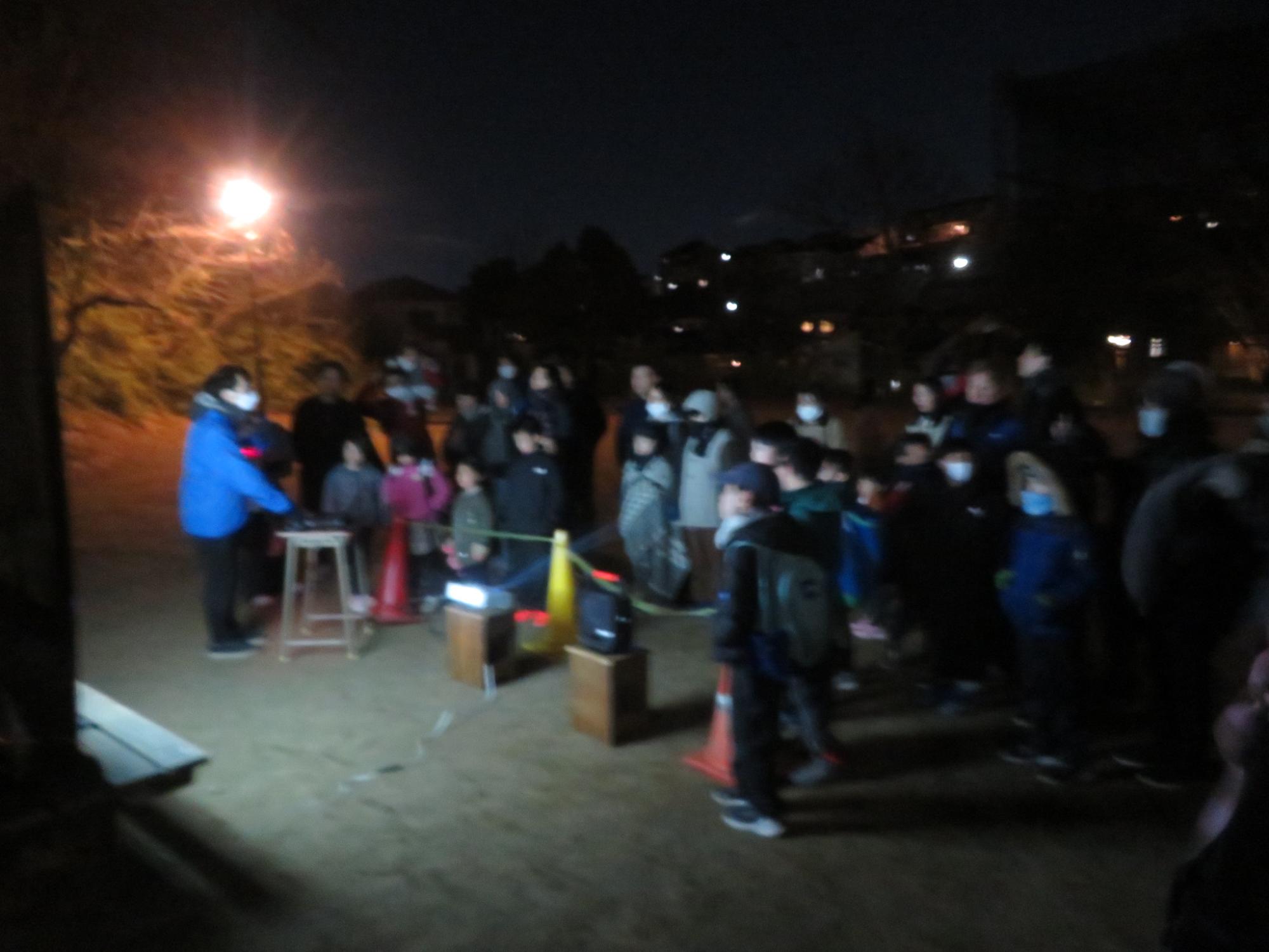 科学館の職員から星の説明を聞く参加者の写真