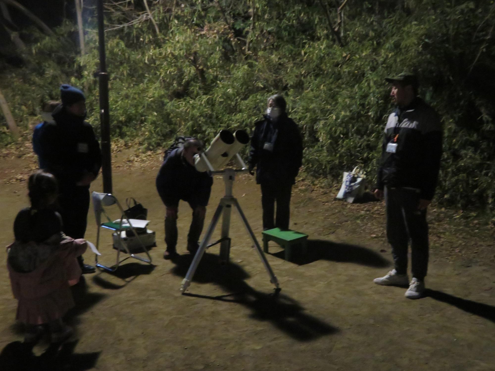 天体望遠鏡で星を観察する成人の写真