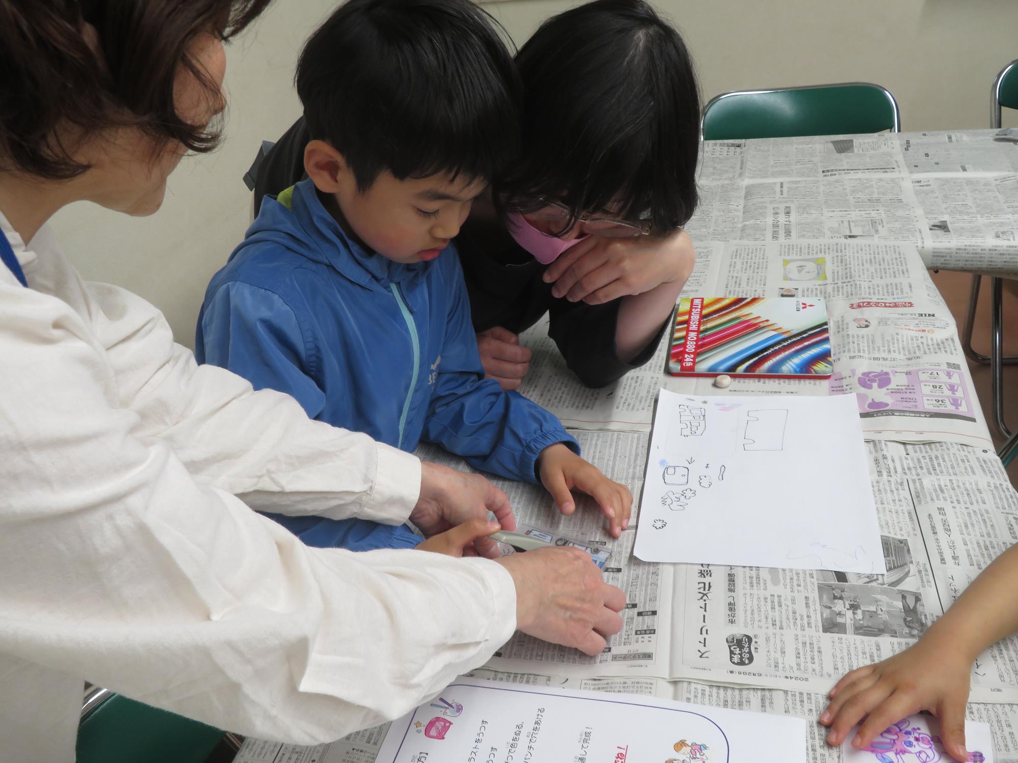 プラバンに絵を描いている幼児親子の写真