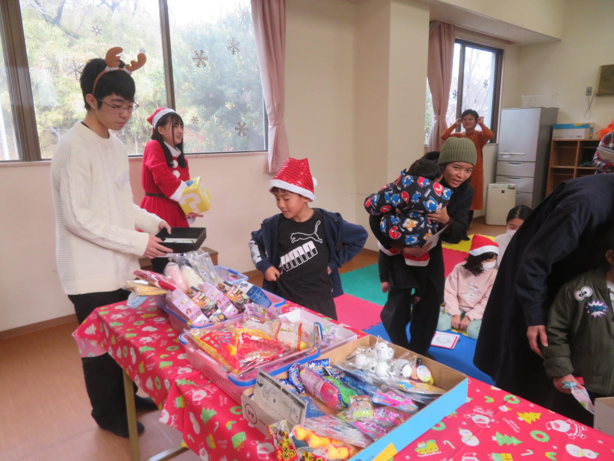 合唱サークルの方とくじびきの景品を選ぶ児童の写真