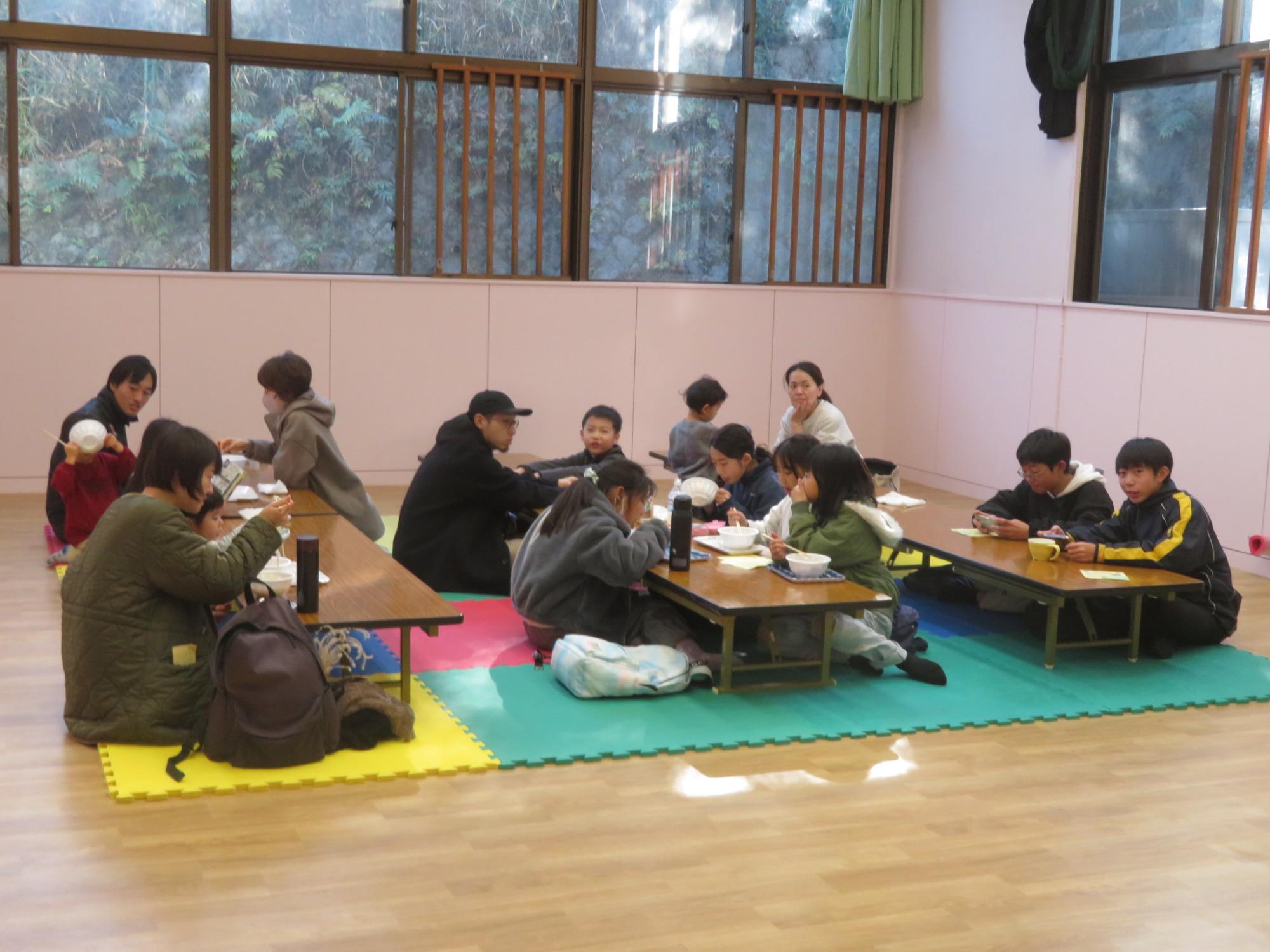 集会室で参加者がうどんを食べている写真
